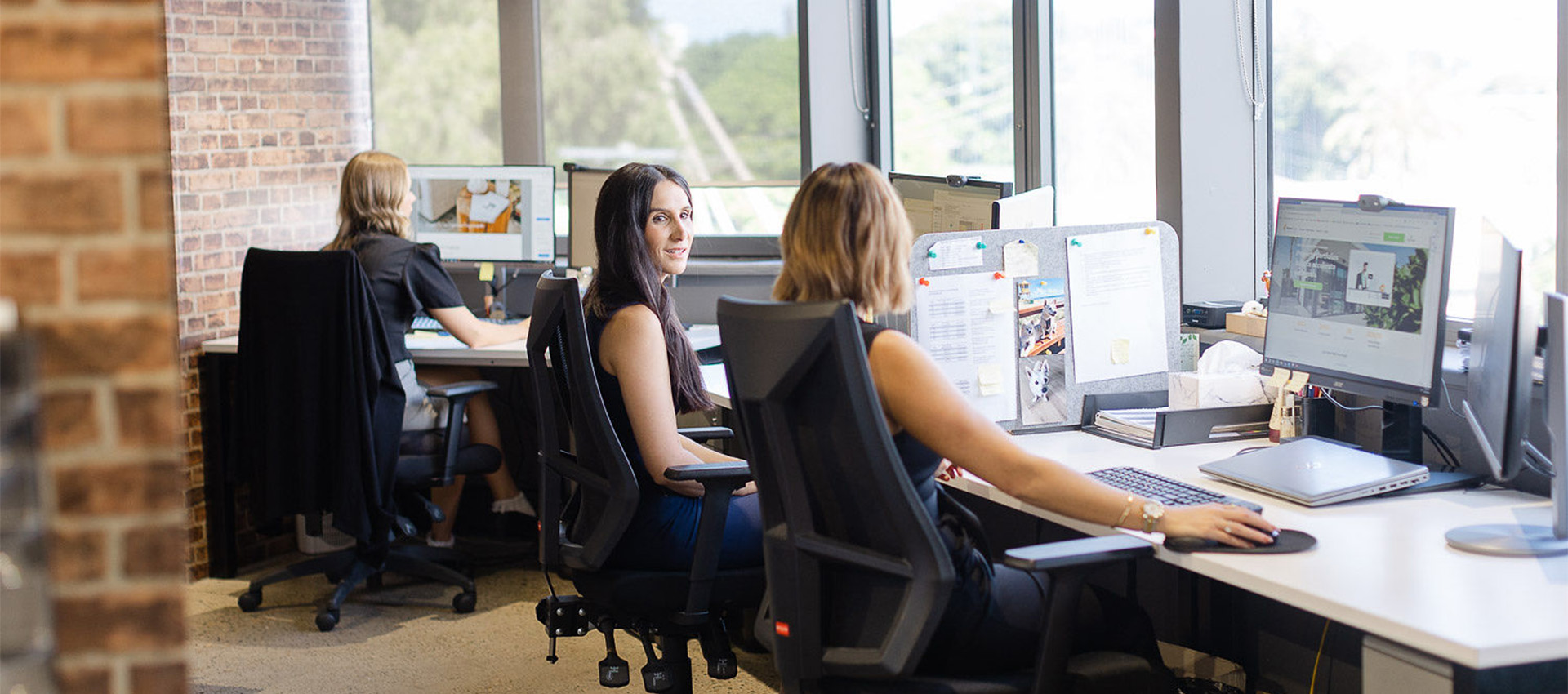 Two women speaking at their desks